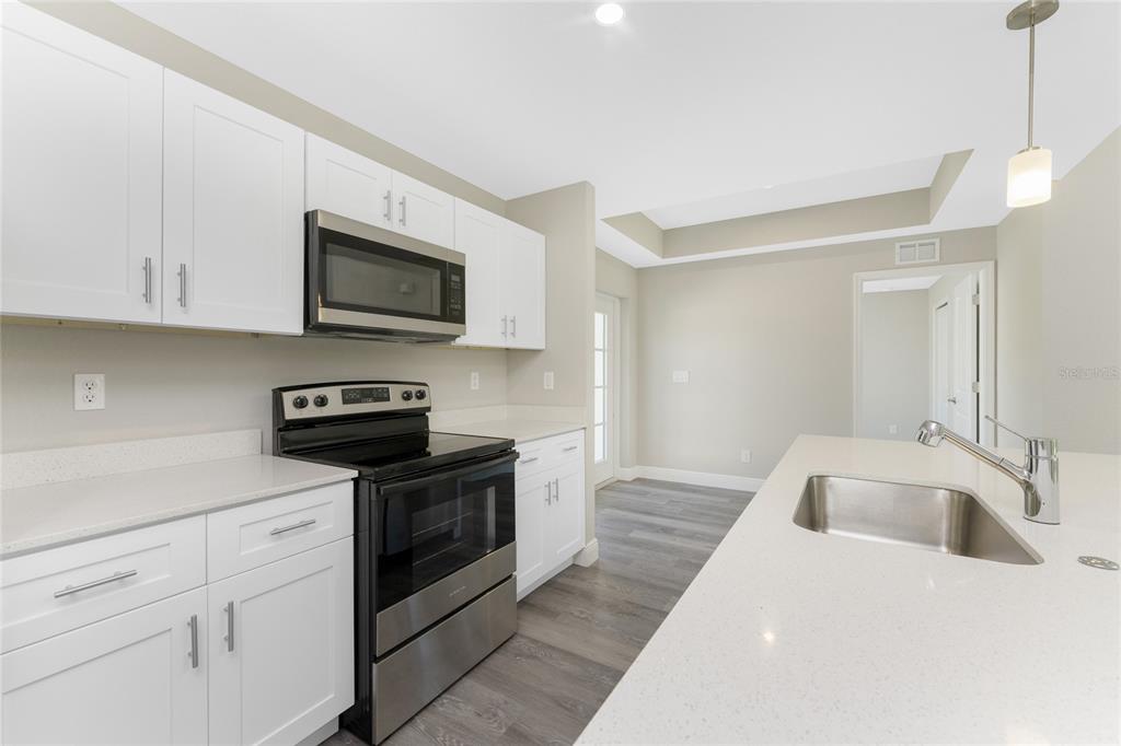 6397 Filbert Street North Port, FL 34288 - Photo 8 of 71 a kitchen with stainless steel appliances granite countertop a sink a stove top oven and white cabinets