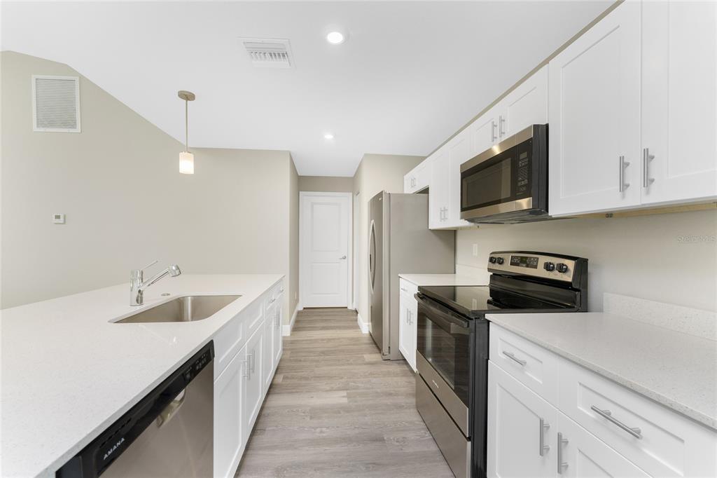 6397 Filbert Street North Port, FL 34288 - Photo 10 of 71 a kitchen with granite countertop sink stainless steel appliances and white cabinets