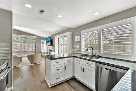 a kitchen with granite countertop white cabinets white appliances and a large window