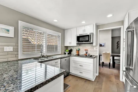 a kitchen with granite countertop a stove a sink and a refrigerator