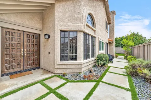a view of a brick house with many windows plants and large tree