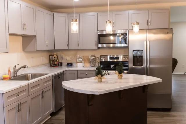 a kitchen with stainless steel appliances granite countertop a sink a stove a refrigerator a center island and cabinets