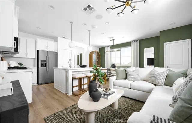 a living room with stainless steel appliances furniture and a kitchen view