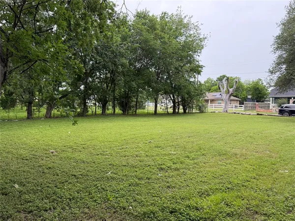 a view of a green field with trees in the background