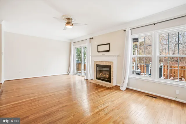 an empty room with wooden floor ceiling fan and windows
