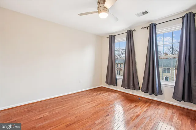 an empty room with wooden floor and fan