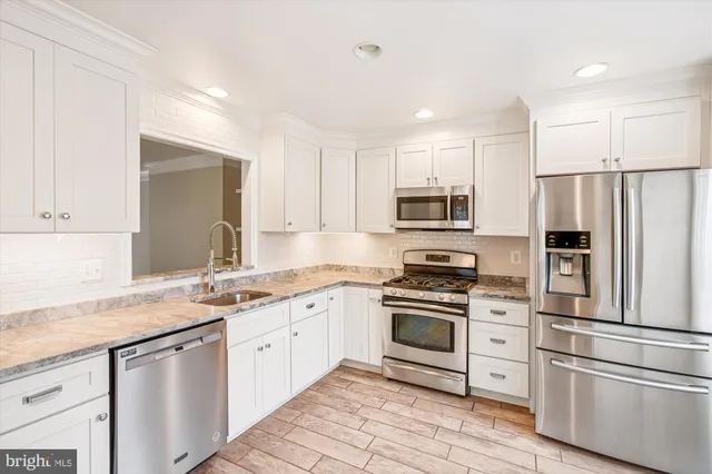 a kitchen with a sink white cabinets and stainless steel appliances
