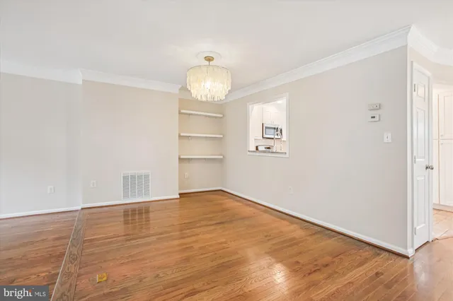 a view of a livingroom with wooden floor and a kitchen