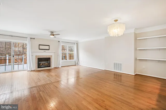 an empty room with wooden floor fireplace and windows