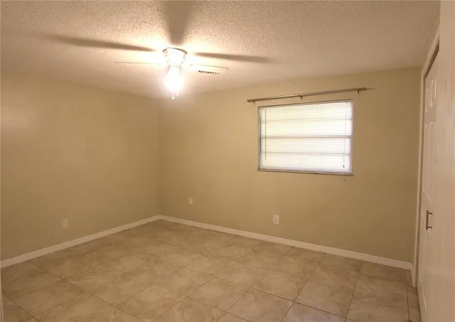 an empty room with a fan and a window