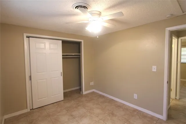 an empty room with closet and a chandelier fan
