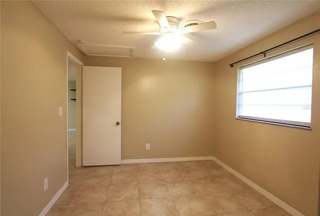 an empty room with a window and a fan