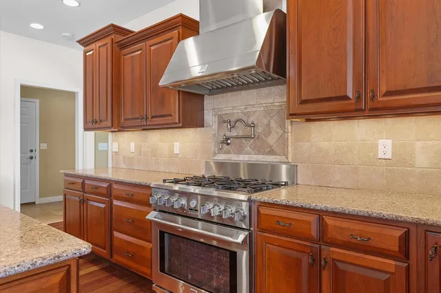 a kitchen with kitchen island granite countertop a stove a sink a refrigerator and a wooden cabinets