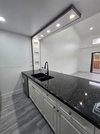 a kitchen with stainless steel appliances granite countertop a sink a stove and a wooden floors