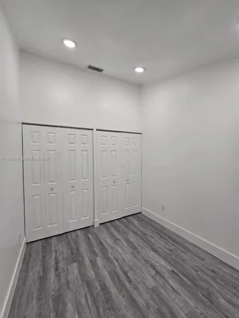 an empty room with wooden floor chandelier and windows