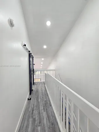 an empty room with wooden floor chandelier fan and windows