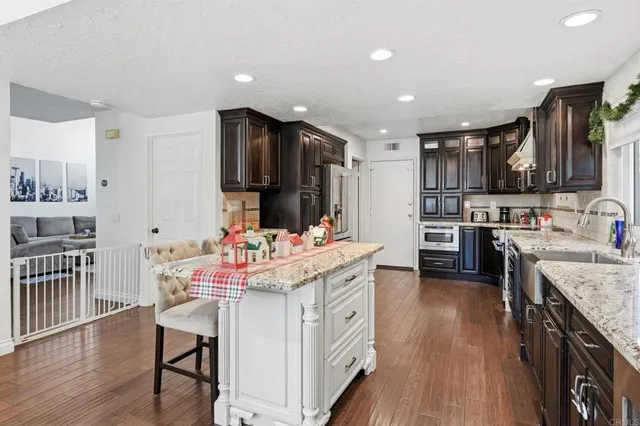 a kitchen that has a lot of cabinets a sink and wooden floor