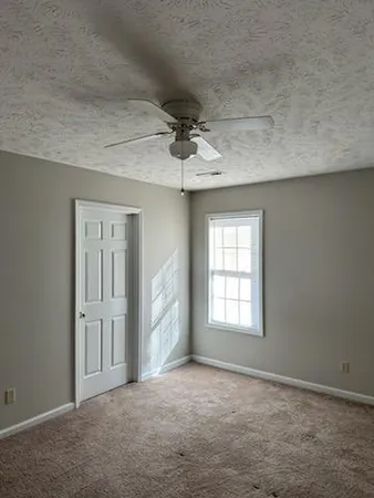 an empty room with windows and ceiling fan
