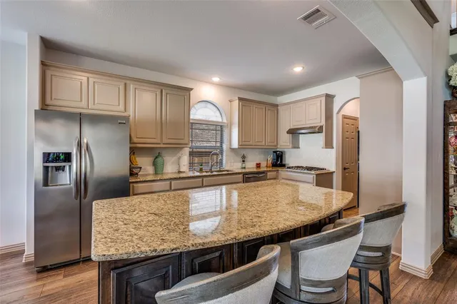 a kitchen with granite countertop stainless steel appliances a refrigerator a stove a sink and cabinets