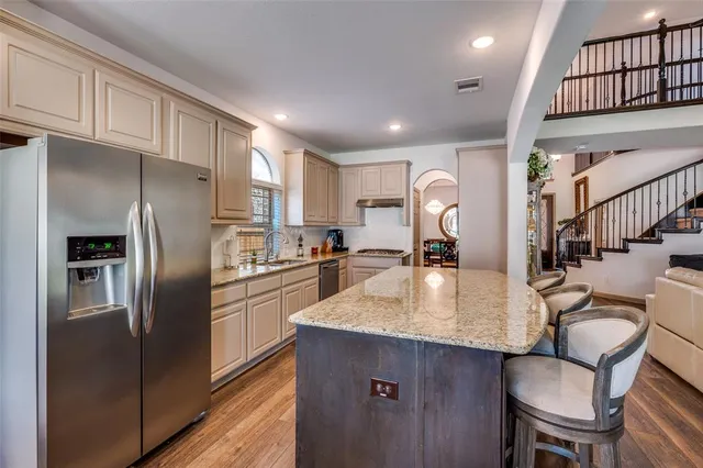 a kitchen with stainless steel appliances granite countertop a refrigerator a sink a stove a dining table and chairs