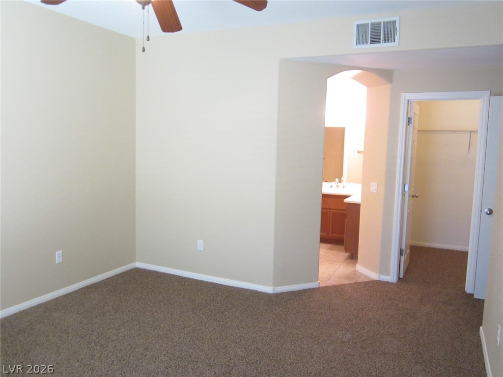 7701 West Robindale Road, Unit 262 Las Vegas, NV 89113 - Photo 23 of 26 A comfortable bedroom featuring soft carpeting and a ceiling fan, offering direct access to a functional primary bathroom.