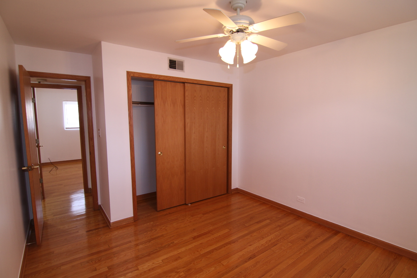 4909 North Harlem Avenue, Unit 1 Chicago, IL 60656 - Photo 6 of 8 an empty room with wooden floor fan and windows