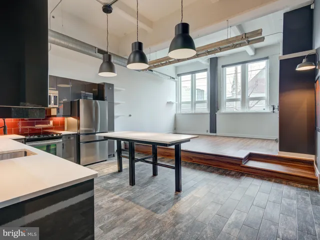 a living room with stainless steel appliances kitchen island granite countertop furniture and a wooden floor