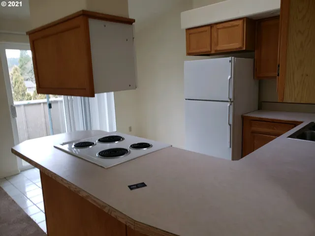 a kitchen with a refrigerator and a stove top oven