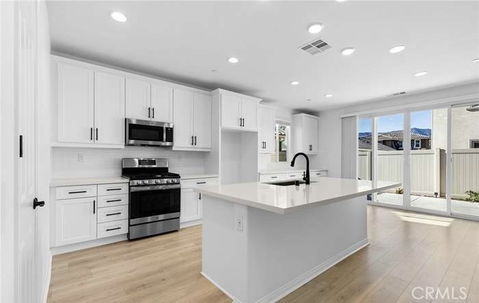 24119 Ashton Corona, CA 92883 - Photo 13 of 45 a large kitchen with stainless steel appliances granite countertop a lot of counter space and wooden floors