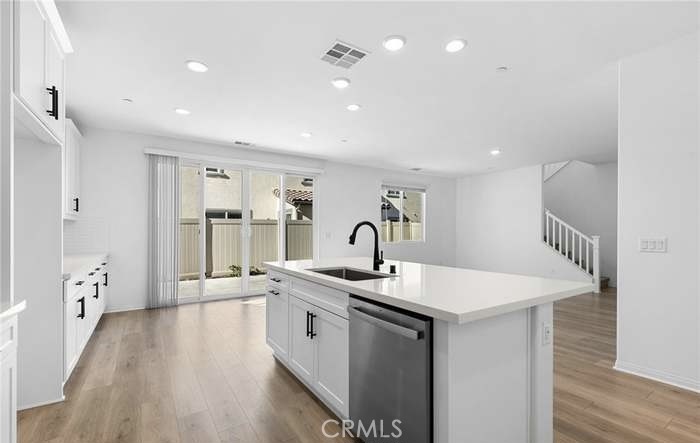 24119 Ashton Corona, CA 92883 - Photo 16 of 45 a hall with kitchen island a sink dishwasher a dining table chairs with wooden floor