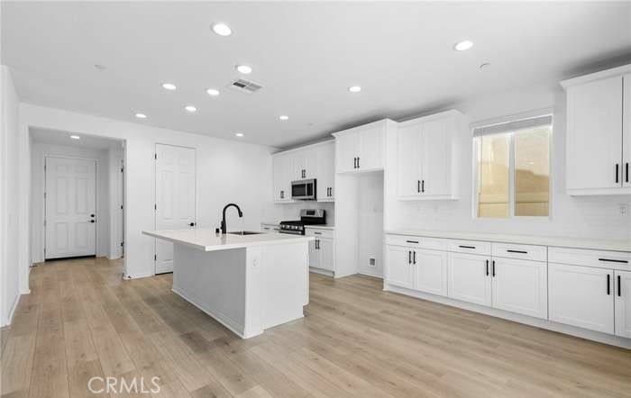 24119 Ashton Corona, CA 92883 - Photo 17 of 45 a large white kitchen with white cabinets and stainless steel appliances