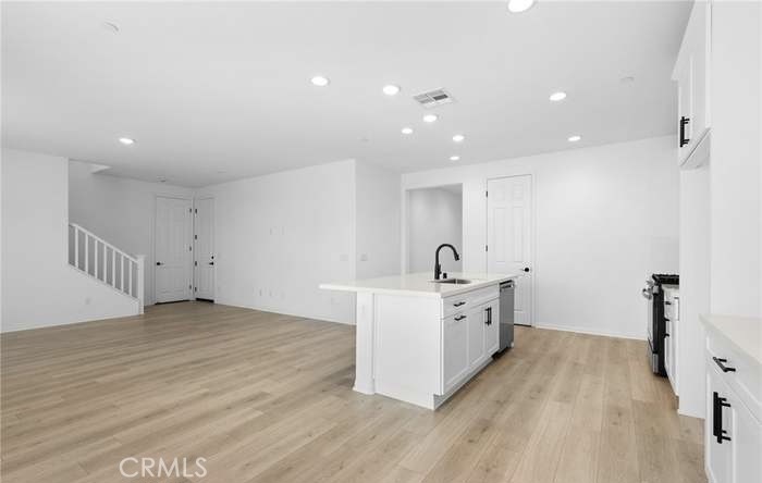24119 Ashton Corona, CA 92883 - Photo 20 of 45 a large white kitchen with a stove a sink a refrigerator and white cabinets with wooden floor