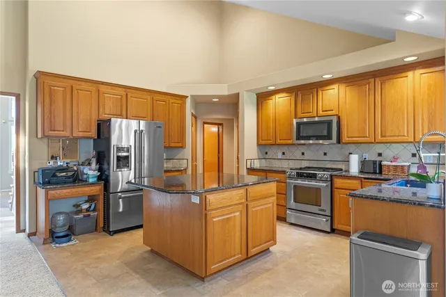 a kitchen with stainless steel appliances granite countertop a sink a stove and a refrigerator