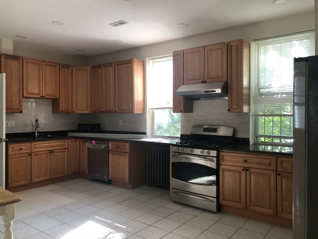 16 Copenger Street, Unit 2 Boston, MA 02120 - Photo 8 of 11 a kitchen with granite countertop wooden cabinets stainless steel appliances and a window