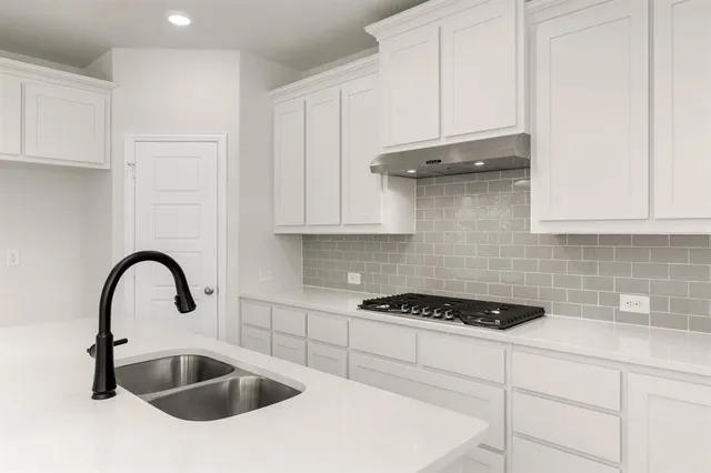 a kitchen with granite countertop a stove a sink and a microwave