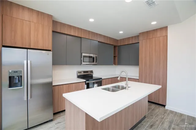 a kitchen with stainless steel appliances granite countertop a sink a refrigerator and a stove