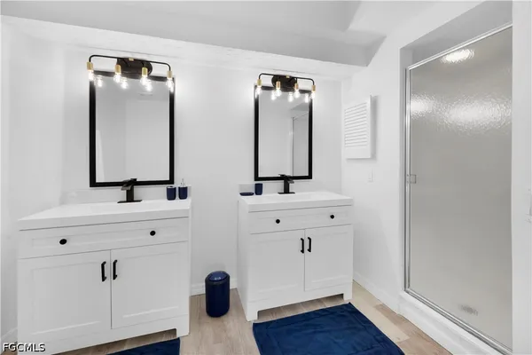 a bathroom with double vanity sink two mirror and a window