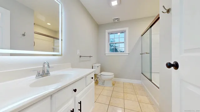 a bathroom with a sink a toilet a mirror and shower