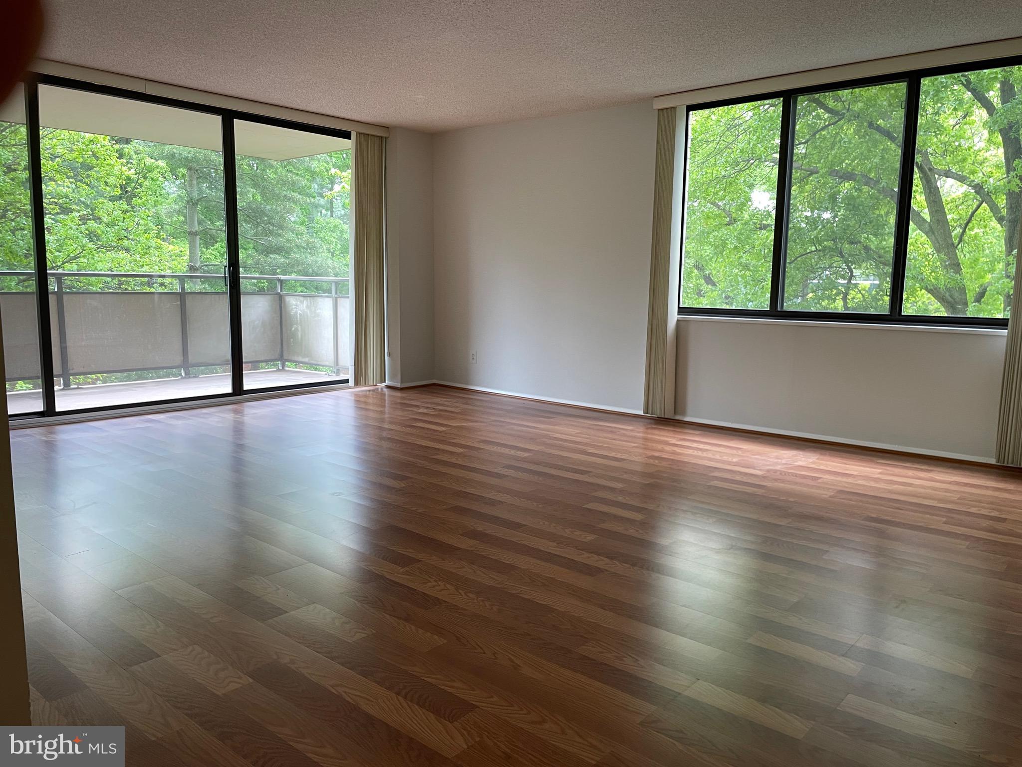 5225 Pooks Hill Road, Unit 228S Bethesda, MD 20814 - Photo 2 of 28 a view of an empty room with wooden floor and a floor to ceiling window