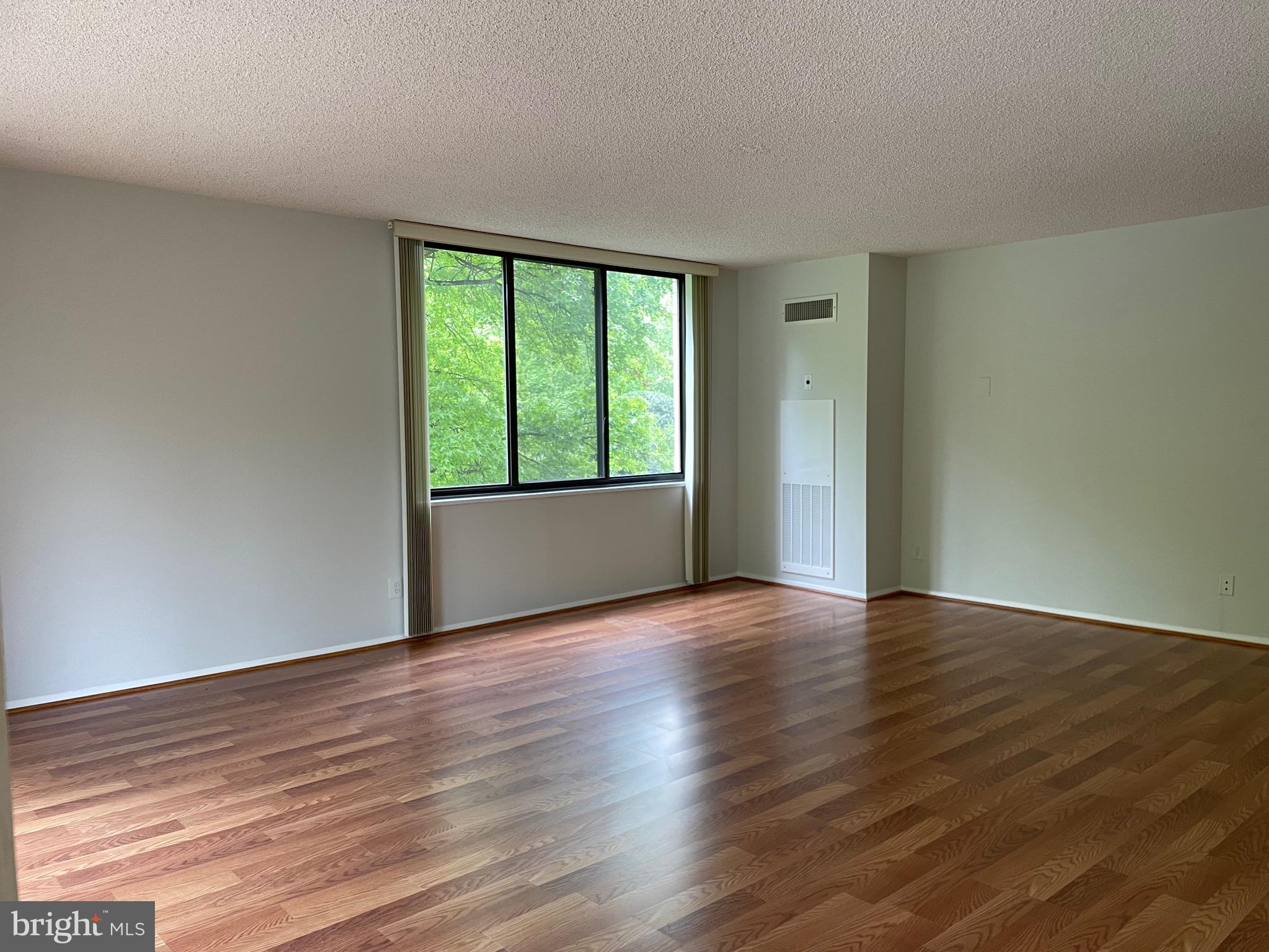 5225 Pooks Hill Road, Unit 228S Bethesda, MD 20814 - Photo 3 of 28 a view of an empty room with wooden floor and a window