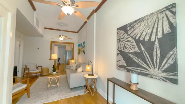 a living room with couches and a dining table with wooden floor