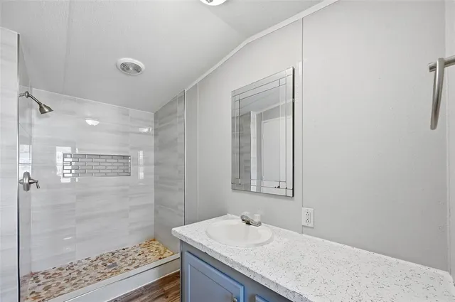 a bathroom with a granite countertop sink a shower and a mirror
