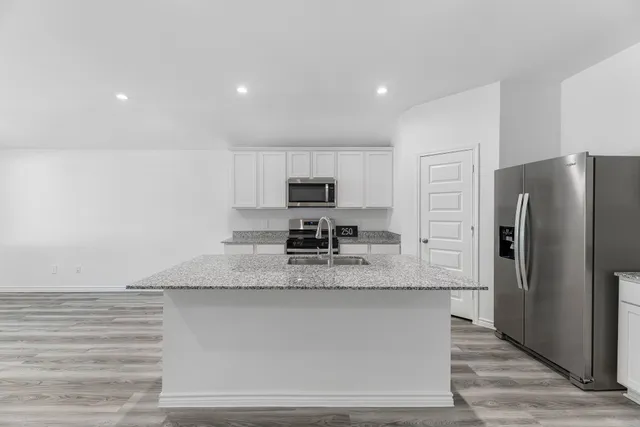 a kitchen with stainless steel appliances granite countertop a refrigerator a stove and a sink with wooden cabinets