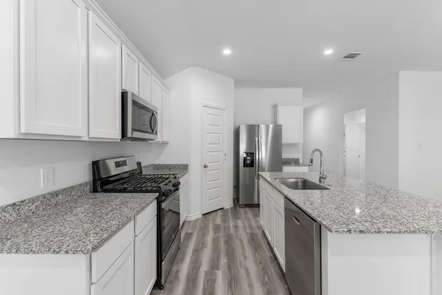 a kitchen with stainless steel appliances granite countertop a sink stove and refrigerator