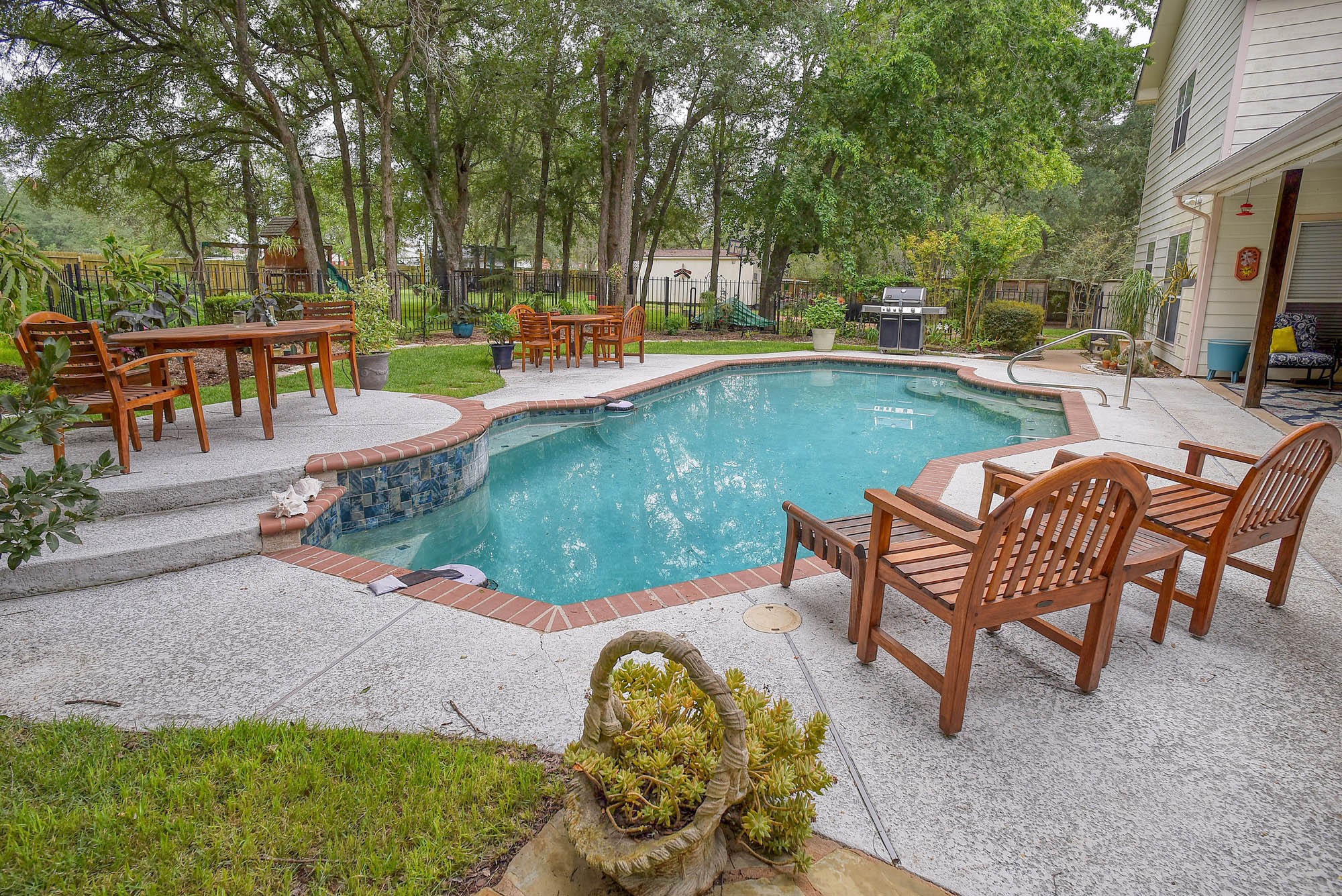 147 Spring Meadow Road Bastrop, TX 78602 - Photo 6 of 40 Freeform swimming pool with a textured deck surround, brick coping, integrated steps, and mosaic tile accents