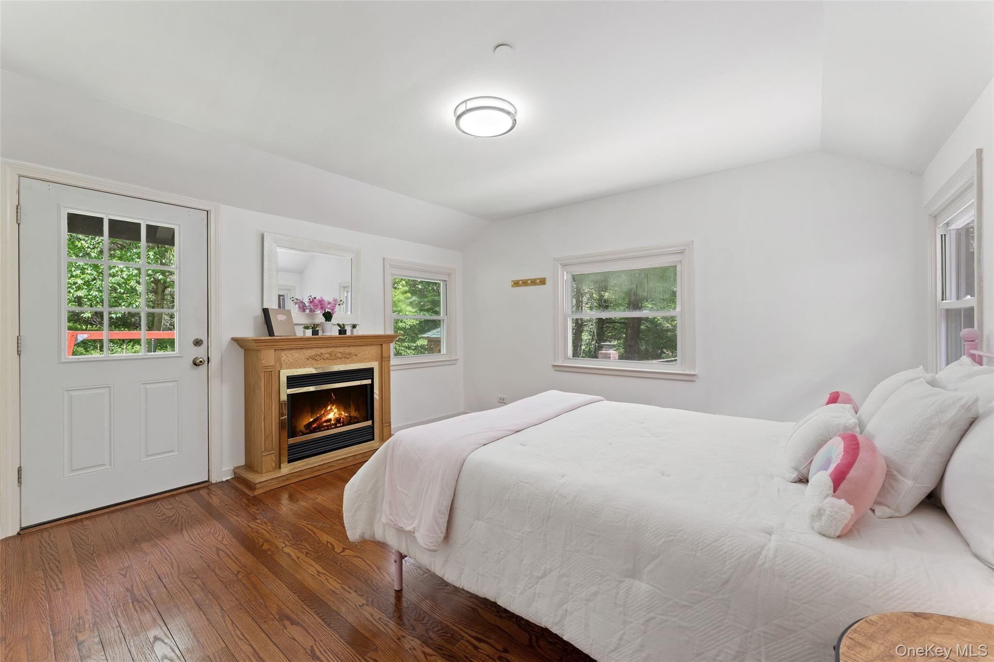 25 Cabin Ridge Road Chappaqua, NY 10514 - Photo 12 of 39 First floor bedroom featuring rich wood-finish flooring, a light wood-finish fireplace, and multiple windows