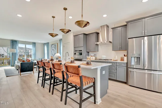 a kitchen with stainless steel appliances granite countertop a refrigerator a stove a sink dishwasher a dining table and chairs with wooden floor