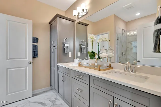 a bathroom with double vanity sinks a vanity a lamp and a mirror