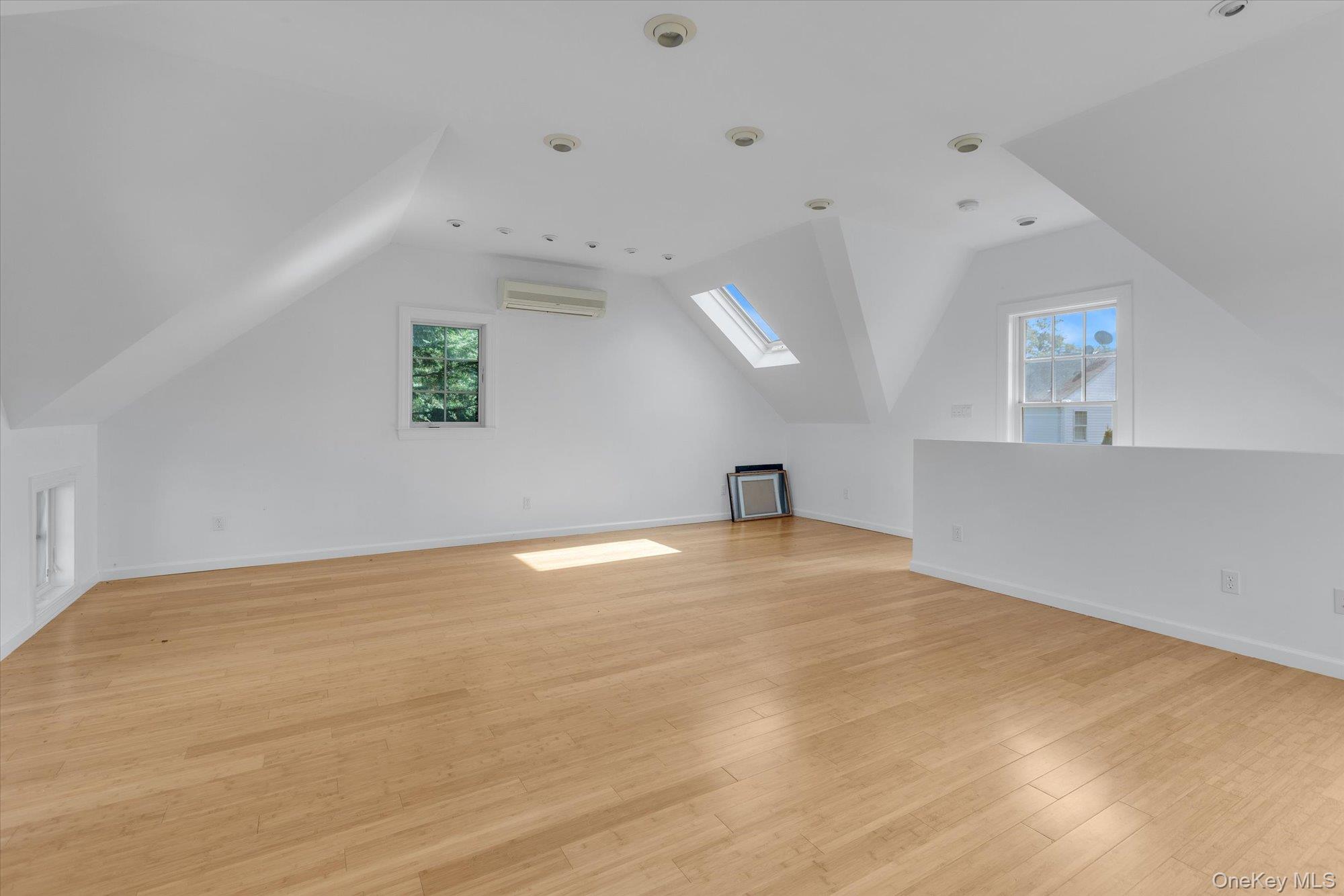 1155 Tasker Lane Greenport, NY 11944 - Photo 18 of 25 Additional living space featuring vaulted ceiling, a skylight, light wood finished floors, and a wall mounted air conditioner