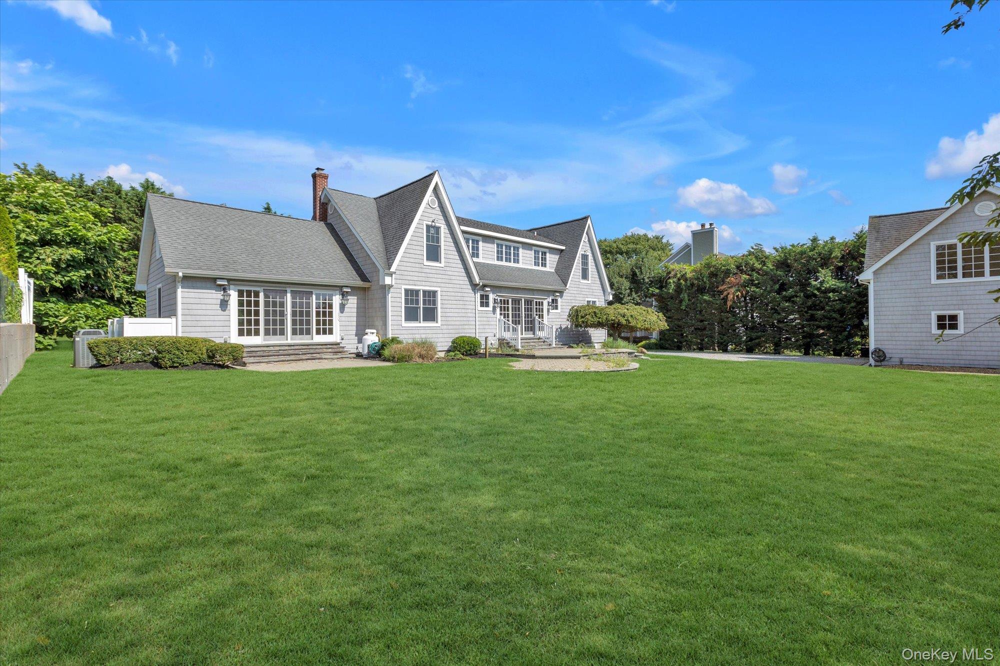 1155 Tasker Lane Greenport, NY 11944 - Photo 22 of 25 Back of property with roof with shingles, a chimney, and a patio